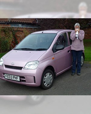 Customer stoodlooking sad next to their old pink car