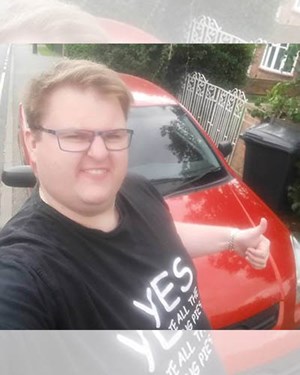 Customer stood with their thumbs up in front of their old red car