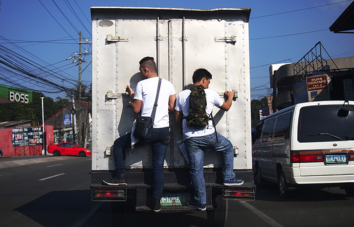 People stood on the back bumper of a lorry