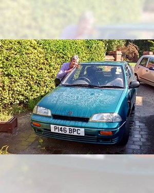 Customer stood smiling and hugging their old car