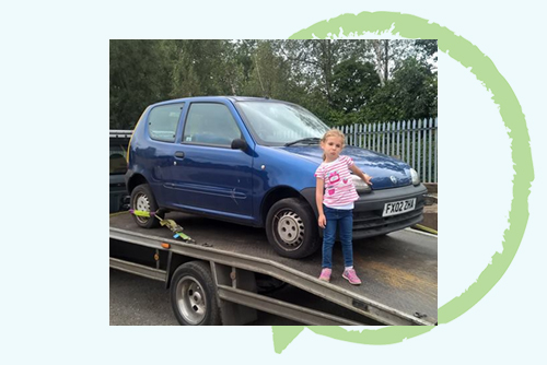 girl stood next to a blue car on a truck