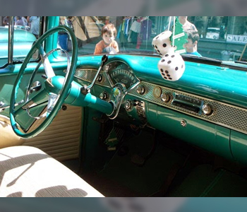 Turquoise retro car interior with fluffy dice hanging from the rear view mirror