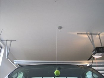 Garage interior with a tennis ball hung on string, a car parked so the ball touches the car window